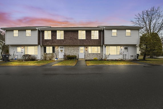 Front view of a two-story townhouse with multiple units and a parking area in front.