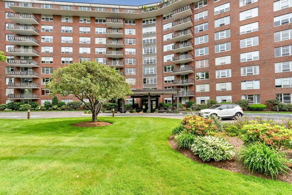 Front view of a multi-story apartment building with balconies and a central entrance.