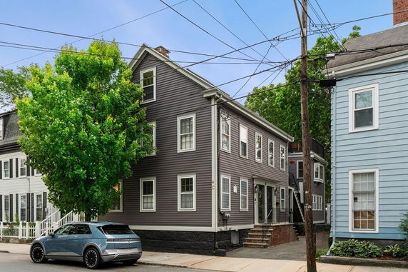 Front view of a multi-story house with gray siding and multiple windows.