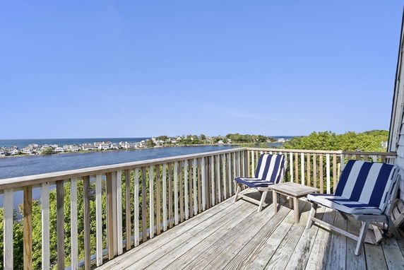 Wide-angle view of a deck overlooking a waterfront area with houses in the distance.