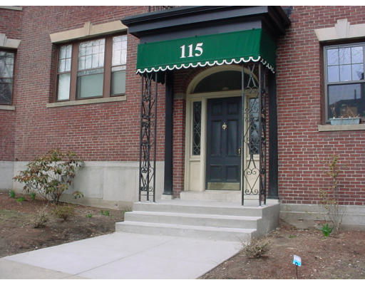 Front view of a brick building with a green awning and entrance canopy.