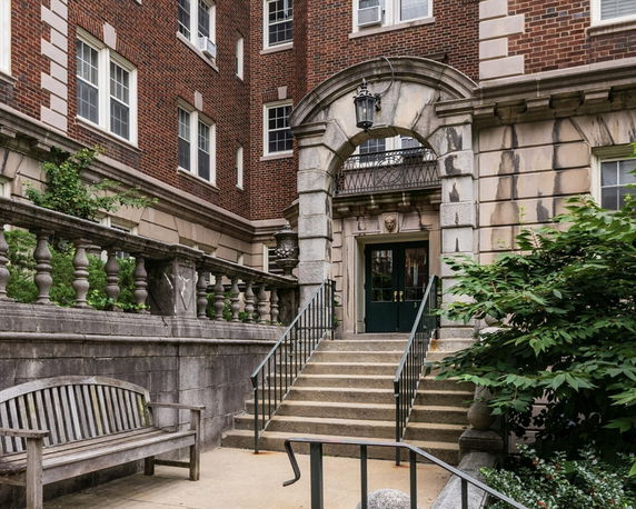 Front view of a brick building with a grand entrance featuring stone steps and decorative columns.