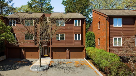 Front view of a multi-story residence with a symmetrical design and three garage doors.