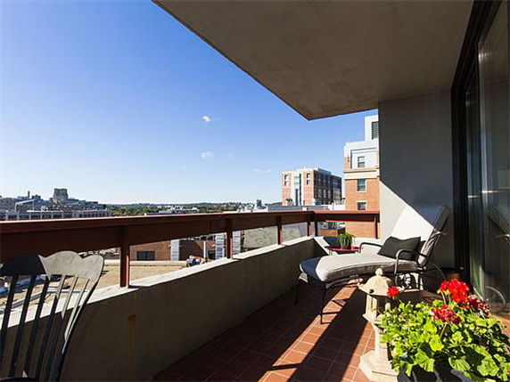 Balcony view with cityscape in the background and outdoor furniture.