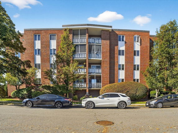 Front view of a multi-story brick apartment building with balconies.