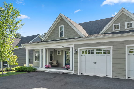 Front view of a house with a covered porch and attached double garage.