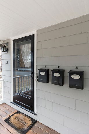 Close-up view of a house entryway with a storm door, mailboxes, and welcome mat.