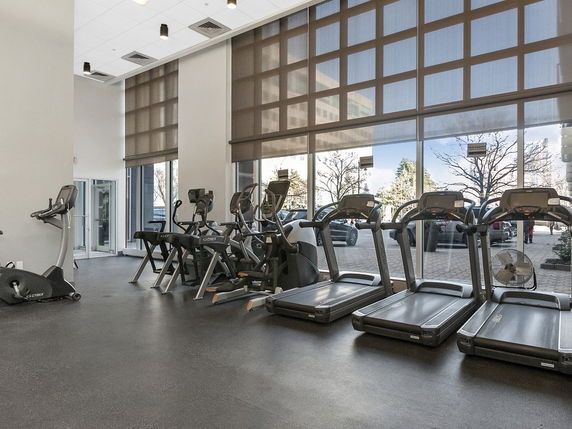 Interior of a gym area with exercise equipment and large windows.