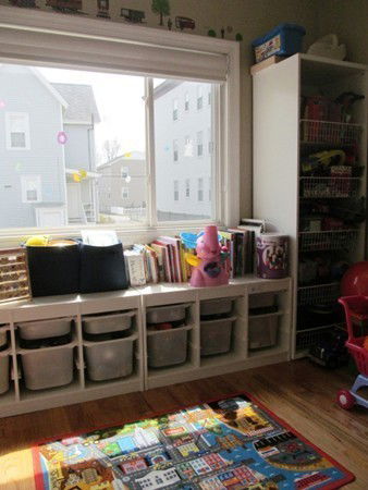 Room with storage bins, toys, and a colorful rug for children.