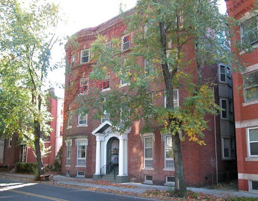 Front view of a multi-story brick building with arched entryway.