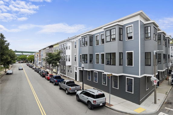 Front view of a multi-story residential building with blue-grey siding and large windows.