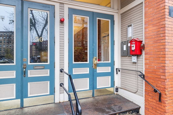 Front entrance view of a building with two blue doors, numbered 50 and 52.