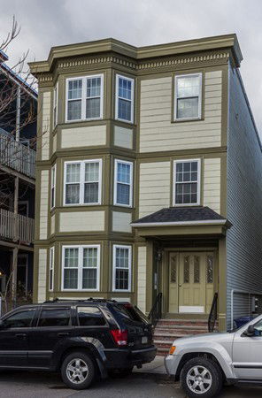 Front view of a three-story house with bay windows and a small entrance porch.