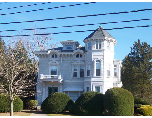 Front view of a multi-story house with a turret and decorative architectural details.