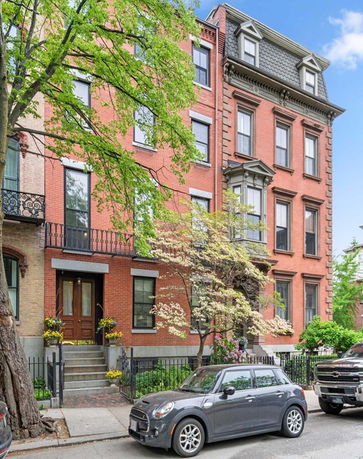 Front view of a multi-story brick building with tall windows and classic architectural details.