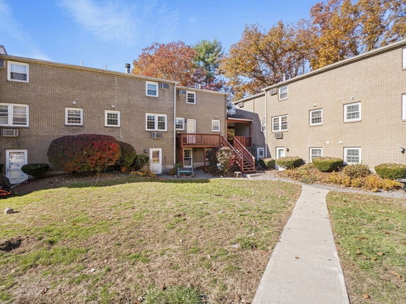 Front view of a multi-story brick building with multiple windows and a wooden staircase.