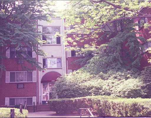 Front view of a multi-story apartment building with red brick exterior and large windows.