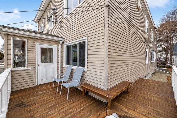 Side view of a two-story house with a wooden deck.
