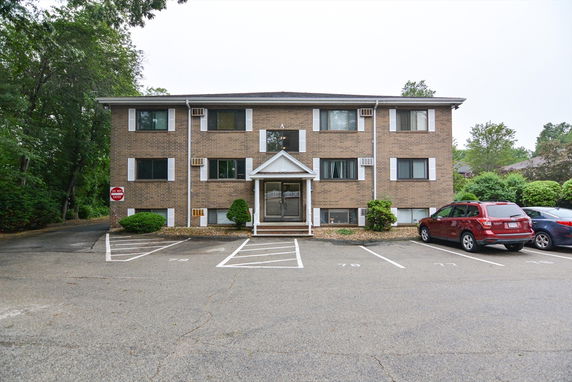 Front view of a three-story brick apartment building with multiple windows and a central entrance.