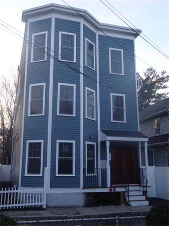 Front view of a three-story house with blue siding and white trim.