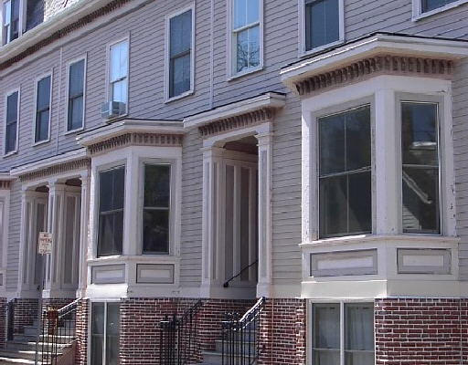 Front view of a row of three-story townhouses with bay windows.