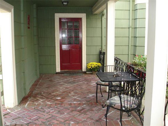 Front view of house entrance with a red door and a small patio area.