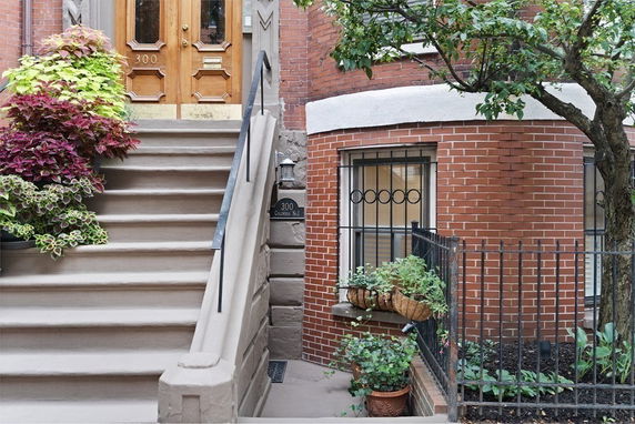 Front view of a brick building with a staircase leading to a wooden door.