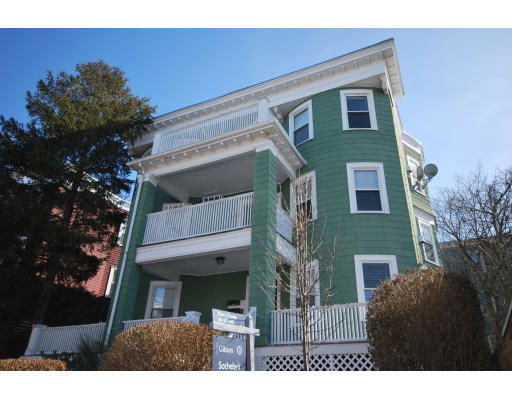 Front view of a green, three-story residential building with balconies.