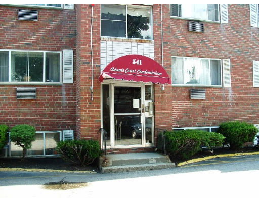 Front view of a condominium building entrance with a red awning.