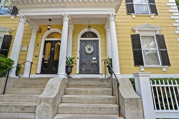 Front view of a house with yellow walls and columns at the entrance.