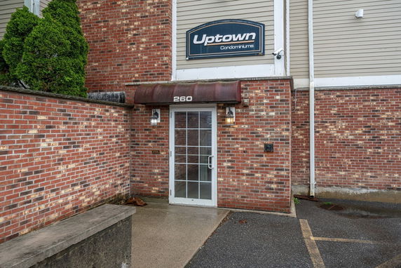 Front view of a brick condominium entrance with a glass door and canopy.