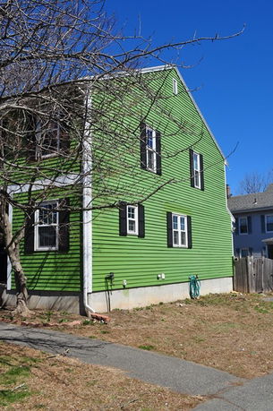 Side view of a green two-story house with black shutters.