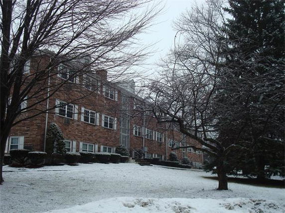 Front view of a multi-story brick apartment building with snow-covered grounds.