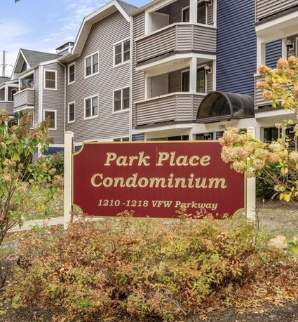 Front view of a multi-story condominium building with balconies and a sign reading 'Park Place Condominium'.