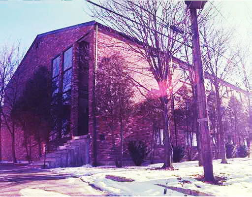 Front view of a two-story brick building with large windows.