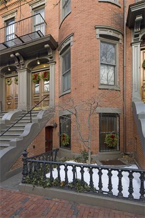 Front view of a multi-story brick building with ornate doors and steps.
