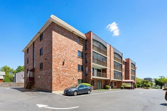 Front view of a multi-story brick apartment building with covered balconies.