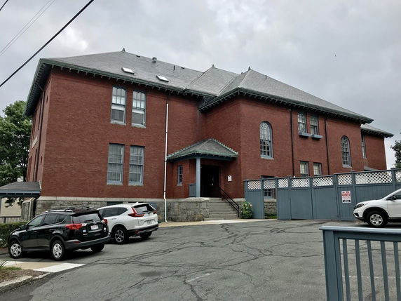 Front view of a two-story brick building with multiple windows and a pitched roof.