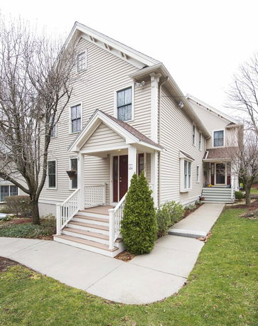 Front view of a two-story house with a porch and white siding.