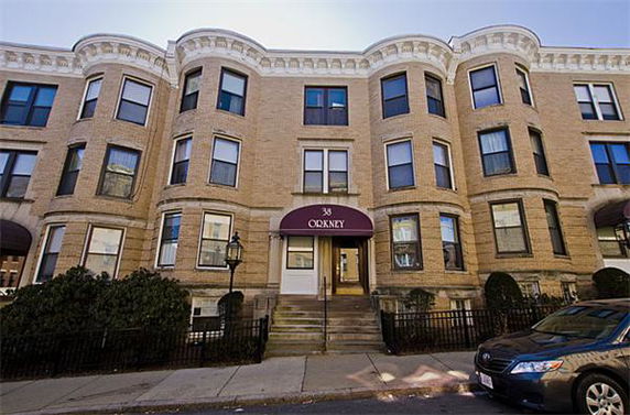 Front view of a multi-story brick apartment building with multiple windows and a central entrance.