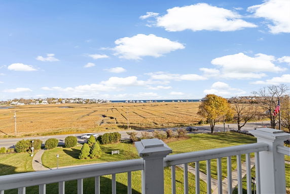 Panoramic view of fields and distant buildings from a balcony.