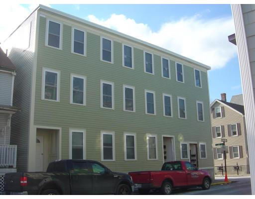 Front view of a three-story building with multiple windows and a green facade.