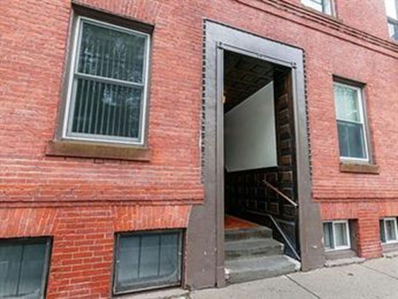 Front view of a brick building entrance with large windows.