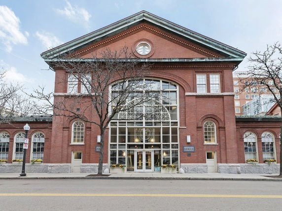 Front view of a red brick building with large windows and arched entrances.