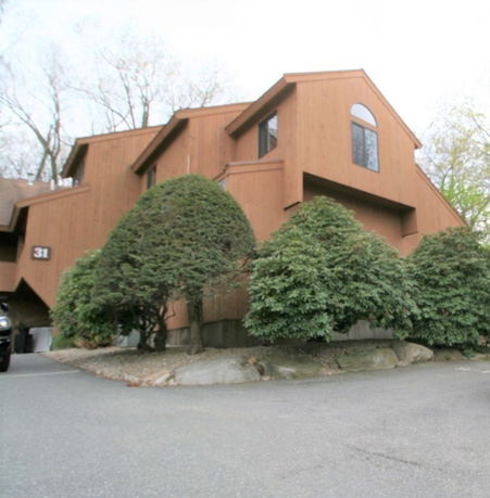 Front view of a multi-story house with a wooden exterior and large windows.