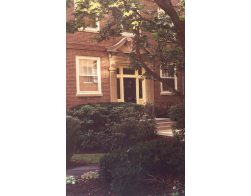 Front view of a brick house with large windows and a decorative entryway.