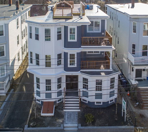 Front view of a multi-story building with balconies and a rooftop deck.