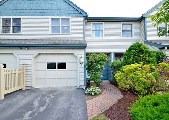 Front view of a two-story house with an attached garage and a paved walkway.