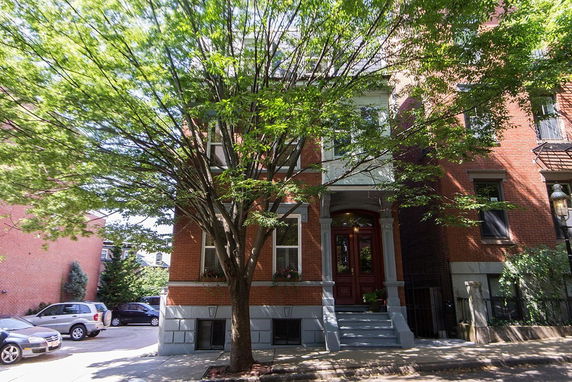 Front view of a three-story red brick house with large tree at the front.