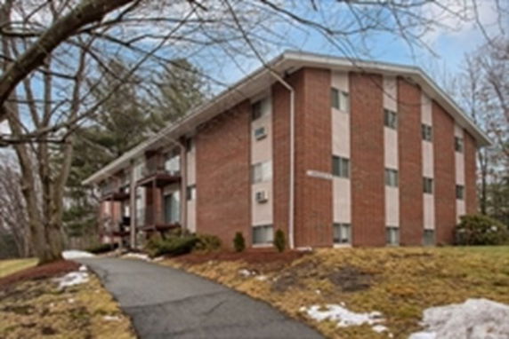 Front view of a multi-story brick apartment building with several windows.